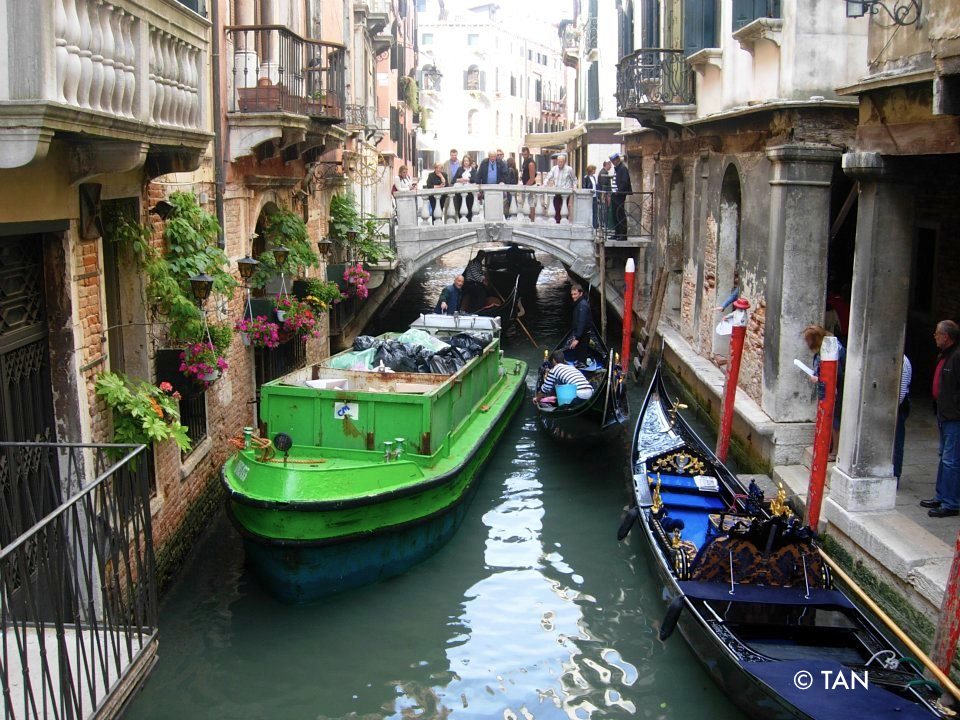 Garbage collection boat and gondolas in Venice, tourist tax